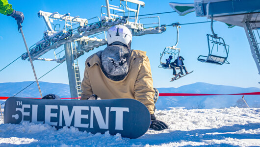 A guest on a snowboard at the top of Peak Express lift at Massanutten Resort